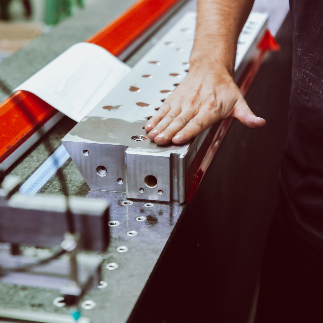 Hand bei der letzten Kontrolle und Nachbearbeitung eines Metallteils.