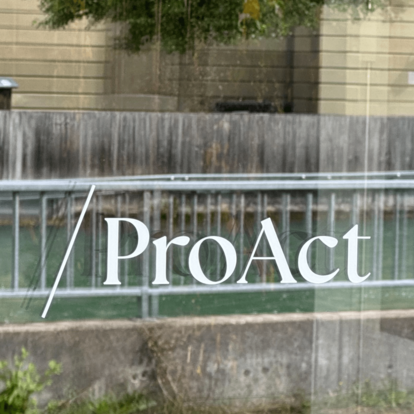 Proact Schriftzug an der Glasfassde, in der Spiegelung die Aare