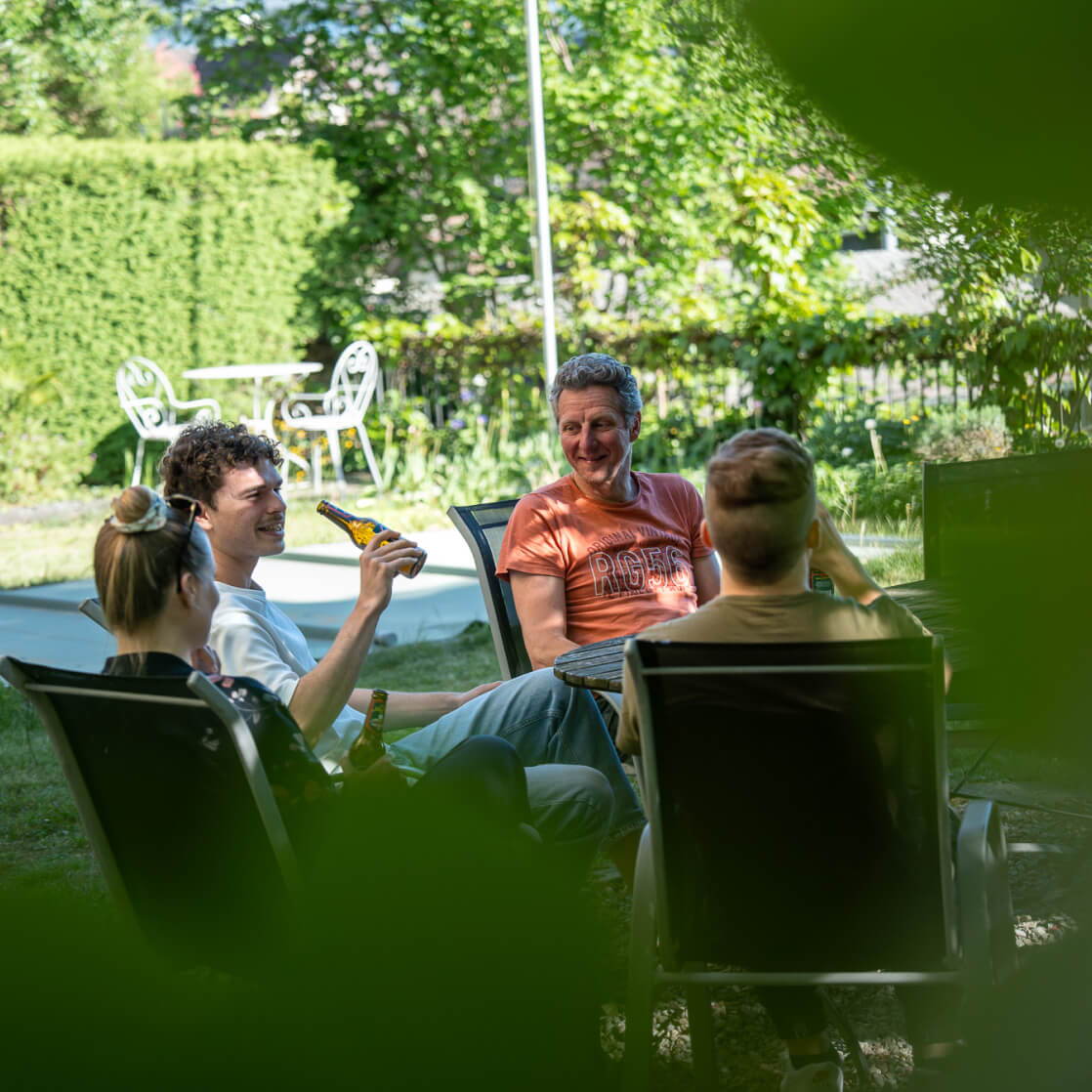 Mitarbeitende von cmsbox sitzen gemeinsam im Garten und tauschen sich in entspannter Atmosphäre aus.
