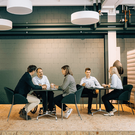 Proact Moodbilder Personen sitzen an Tischen und trinken Cafe und sprechen miteinander.